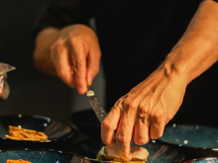 Hands folding and cutting a filled tortilla on a dark plate under low kitchen light